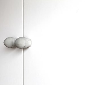 Puede incluir: Dos pomos de puerta de cerámica blanca con forma redondeada.