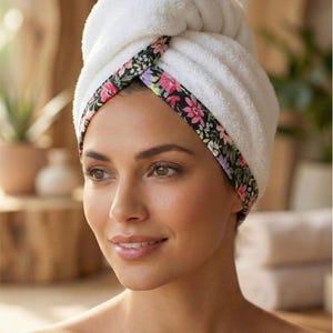 Puede incluir: Una toalla de rizo blanca para el cabello con un borde negro y un patr&oacute;n floral colorido de flores rosas, moradas y blancas. La toalla est&aacute; asegurada en un estilo de turbante retorcido alrededor de la cabeza. La imagen incluye el texto Style - 11.