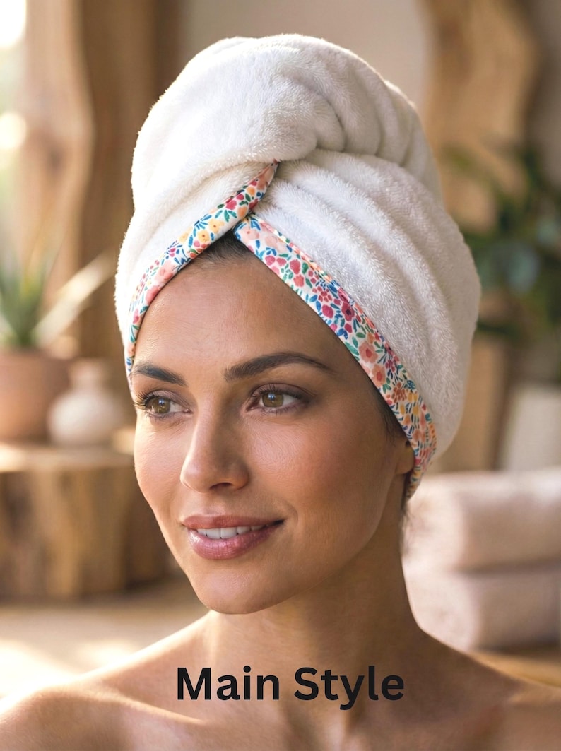 Puede incluir: Una toalla de pelo blanca y afelpada con un borde de estampado floral colorido en tonos rosa, naranja y verde. La toalla est&aacute; enrollada en forma de turbante alrededor de la cabeza, con el texto Main Style impreso en la parte inferior.