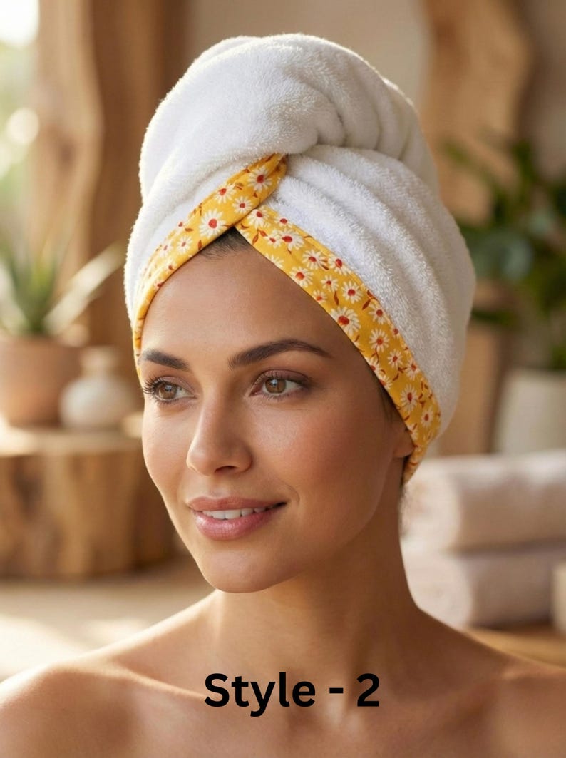 Puede incluir: Una toalla para el cabello blanca con un borde amarillo que presenta un patr&oacute;n repetitivo de margaritas blancas. La toalla est&aacute; asegurada en un estilo de turbante retorcido alrededor de la cabeza. El texto "Style - 2" aparece en negro.