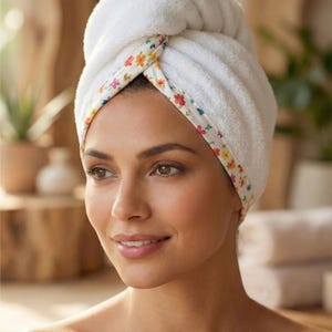 Puede incluir: Una toalla de pelo de felpa blanca con un borde decorativo que presenta un colorido patr&oacute;n floral de peque&ntilde;as flores naranjas, rosas y amarillas. La toalla est&aacute; retorcida y asegurada en la parte superior de la cabeza. El texto "Style - 9" aparece abajo.