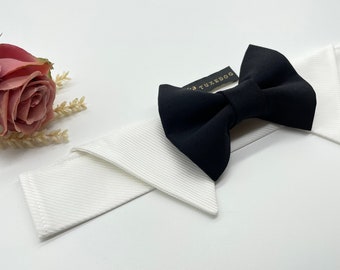 May include: A black bow tie with a white collar, the bow tie has the text "TUXEDOG" on it.