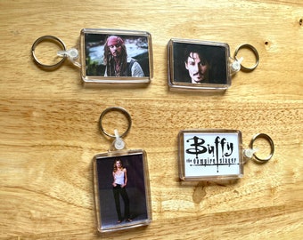 May include: Four keychains with clear plastic frames and metal rings. The keychains feature images of a person with long hair, a person with short hair, a person with long hair, and the text "Buffy the Vampire Slayer".