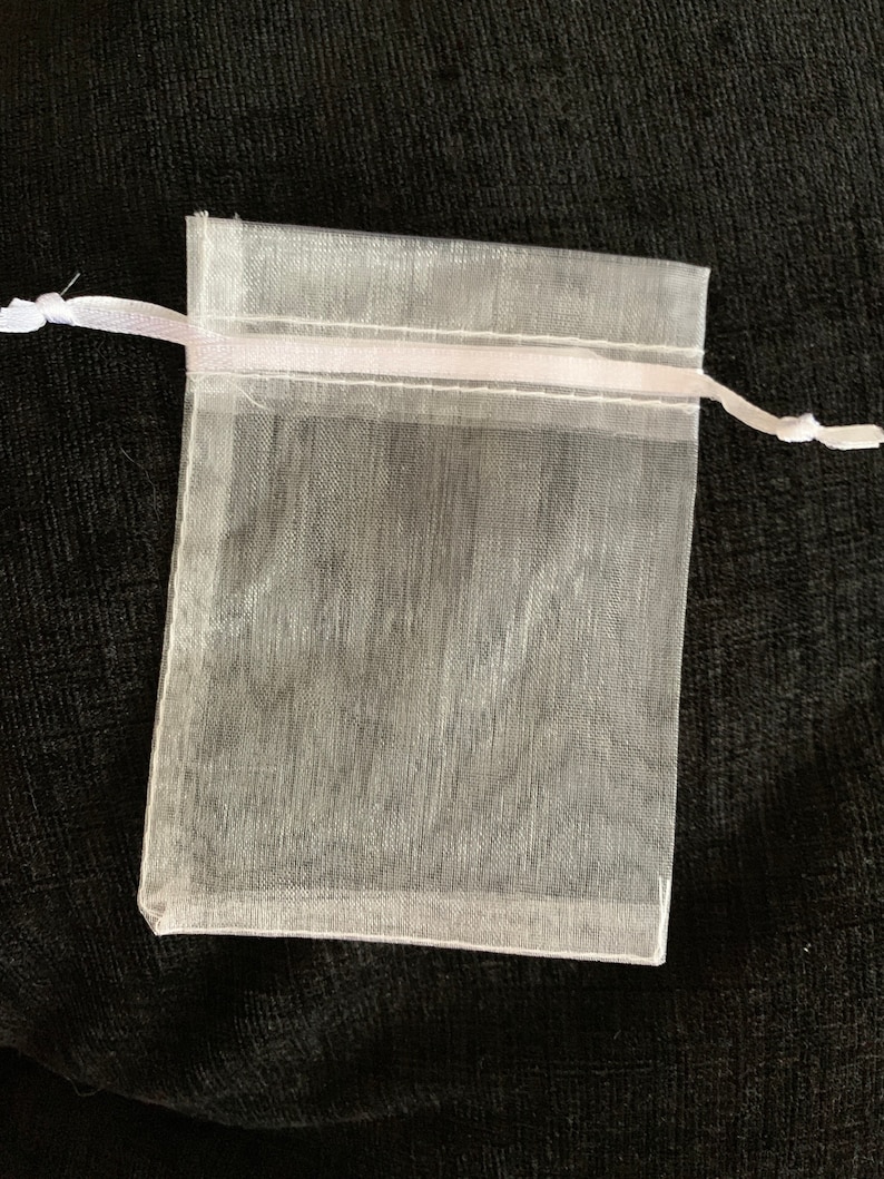 Puede incluir: Una bolsa de regalo de organza blanca transparente con un cord&oacute;n de sat&eacute;n blanco.
