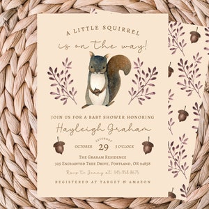 May include: A baby shower invitation featuring a cartoon squirrel holding an acorn. The invitation is cream coloured with brown and purple floral accents. The text reads "A little squirrel is on the way!" and includes the name "Hayleigh Graham", the date "October 29", the time "3 o'clock", the location "The Graham Residence", and the address "325 Enchanted Tree Drive, Portland, OR 94858".