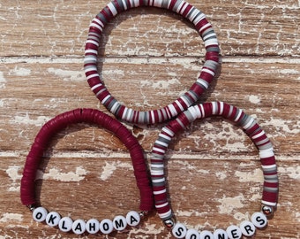 May include: Two red and white beaded bracelets with the words "OKLAHOMA" and "SOONERS" spelled out in white beads.
