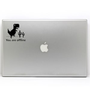 Könnte beinhalten: Ein silberner Laptop mit einer schwarzen pixelartigen Dinosaurier- und Kaktusgrafik und dem Text "You are offline".