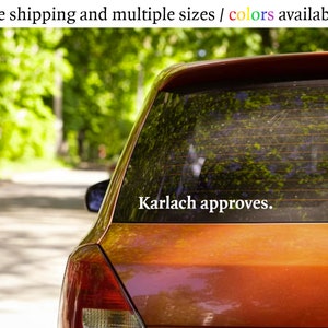 May include: A red car with a white vinyl sticker on the back window that says "Karlach approves."