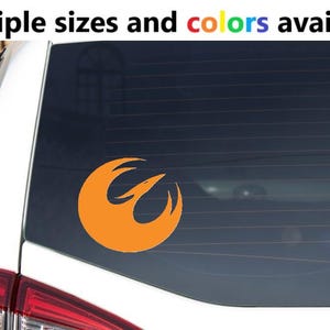 May include: An orange vinyl decal featuring a stylized bird emblem applied to the rear window of a white vehicle. The text above the vehicle reads Multiple sizes and colors available, with the word colors displayed in a rainbow gradient font.