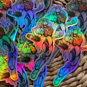 May include: A set of iridescent holographic stickers featuring a female character in a futuristic suit. The stickers are arranged in a pile on a woven wicker surface.