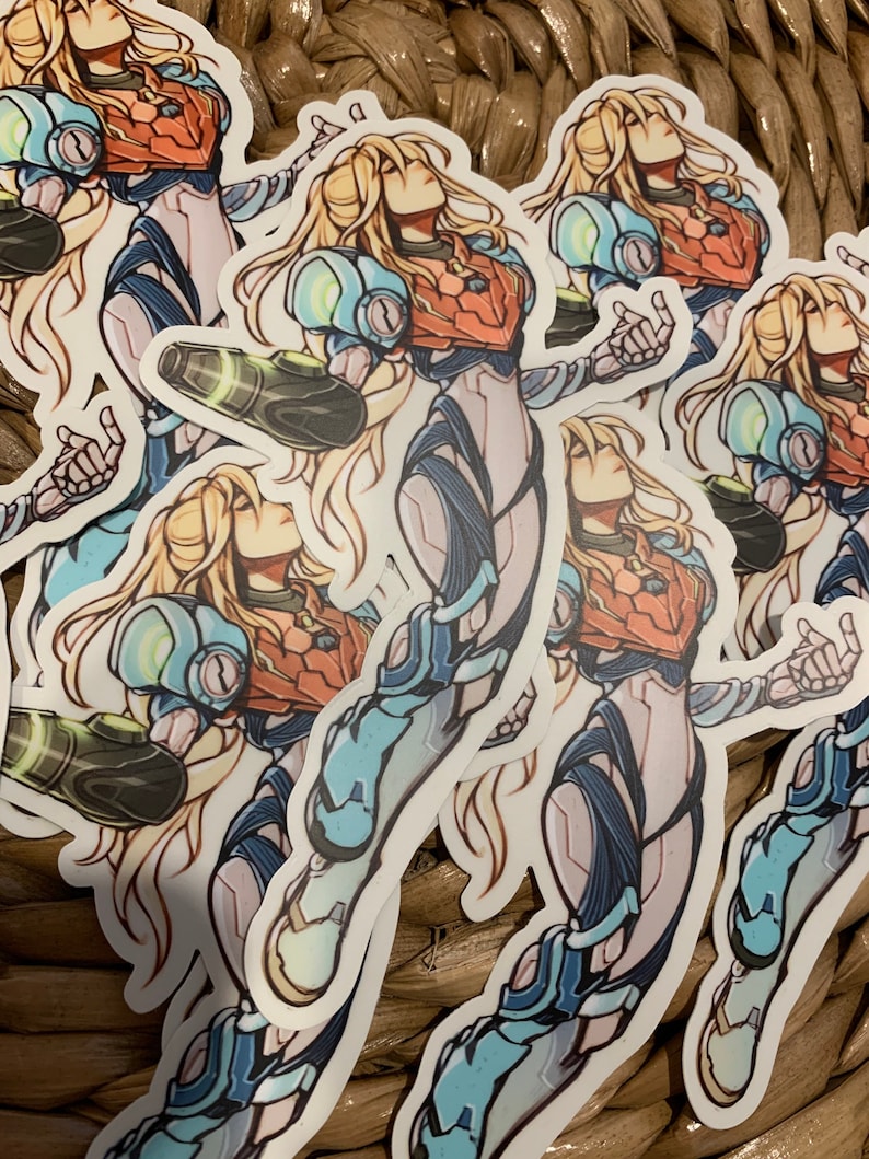 May include: A set of five stickers featuring a female character in a blue and white suit with long blonde hair. The character is holding a weapon in her right hand and has a determined expression on her face.