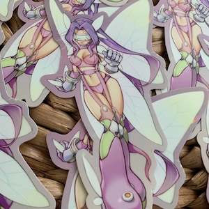 May include: A sticker featuring a purple and green fairy-like character with large wings. The character is wearing a pink and white outfit and has a blindfold over her eyes.