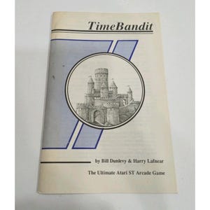 May include: A white manual for the TimeBandit Atari ST arcade game by Bill Dunlevy and Harry Lafnear. The cover features a black and white circular illustration of a stone castle with towers and a blue graphic element in the background.