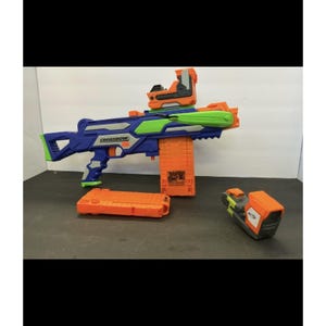 May include: A blue, orange, and lime green toy crossbow with the word CROSSBOW printed on the side. The toy includes a detachable orange magazine, a mounted orange and grey sight, and a separate orange and grey accessory piece with a Nerf logo.