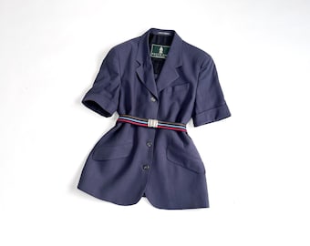 May include: A navy blue short-sleeved blazer with a multi-colored striped belt. The blazer has a classic design with a notched collar, two front pockets, and button closures. The belt features red, blue, and black stripes. The blazer is a size medium.