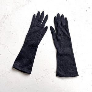 May include: A pair of black elbow-length gloves with a delicate eyelet pattern.