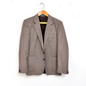 May include: A brown and white checkered blazer with a single button closure. The blazer has two flap pockets and a brown lining.