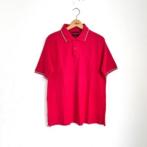 May include: A red short-sleeved polo shirt with a white and black collar and cuffs.