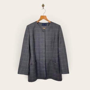 May include: A dark gray blazer featuring a white grid pattern, a collarless round neckline, and a single front button closure. The garment includes two front pockets and is displayed on a wooden hanger with the text Alexon visible.