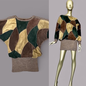 Peut inclure: Un haut patchwork aux tons marron, vert et or. Le haut présente des manches chauve-souris et un bas en tricot côtelé. Le vêtement est présenté sur un mannequin, soulignant son motif et sa texture uniques. La longueur du haut est d'environ 60 cm.