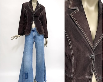 May include: A brown suede jacket with white stitching and a single button closure. The jacket has a classic blazer style with a notched lapel.