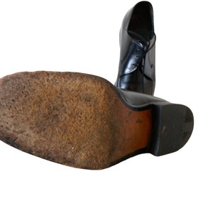 May include: Black leather dress shoe with a lace-up closure. The shoe has a brown leather sole and a rubber heel.