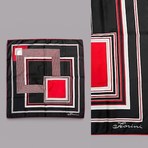 Può includere: Una sciarpa quadrata nera con un design geometrico con quadrati e linee rosse, bianche e marroni. La sciarpa ha un bordo rosso e il nome "Fiorini" è stampato in corsivo. La sciarpa è probabilmente di seta.
