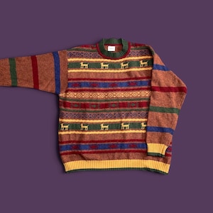 May include: A long-sleeve knit sweater featuring a multi-colored horizontal striped pattern in shades of rust, green, blue, and yellow. The design includes repeating motifs of small yellow dogs, intricate geometric bands, and a ribbed crew neckline.