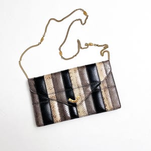 May include: A black and brown striped clutch bag with a gold chain strap.