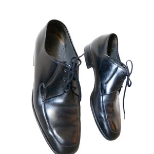 May include: A pair of black leather lace-up shoes. The shoes have a classic design and are in good condition.