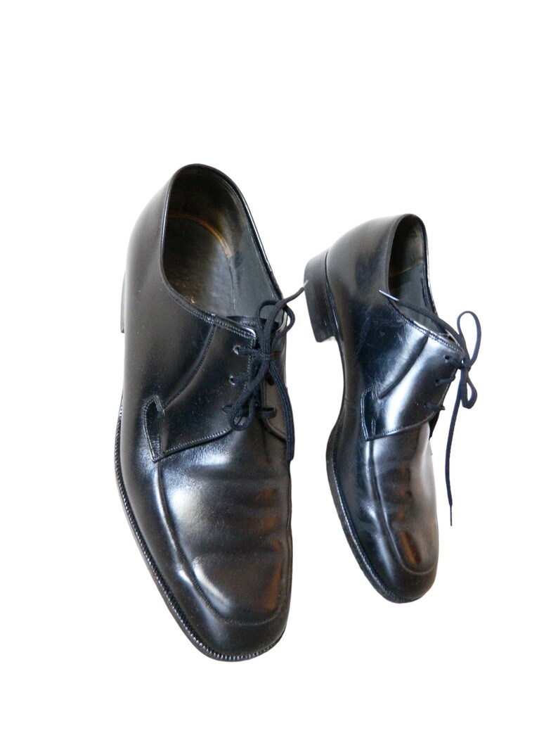 May include: A pair of black leather lace-up shoes. The shoes have a classic design and are in good condition.