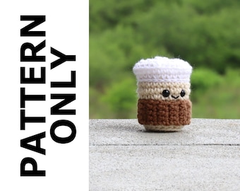 May include: A crocheted coffee cup with a smiling face. The cup is brown at the bottom, beige in the middle, and white at the top. The words "PATTERN ONLY" are printed vertically on the left side of the image.