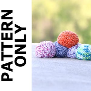 May include: A collection of colorful, crocheted spheres in shades of orange, purple, blue, and green. The spheres are stacked on a light gray surface. The text "PATTERN ONLY" is printed vertically in black on a white background.