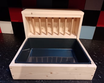 May include: A wooden pet feeder with a removable tray and a slatted hay rack. The feeder is made of natural wood and has a dark blue plastic tray.