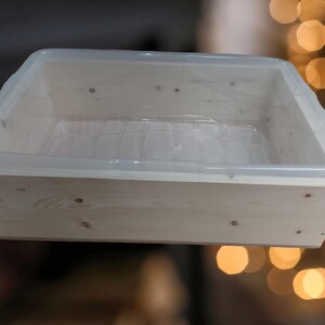 May include: A white wooden box with a clear plastic insert. The box is made of unfinished wood and has a simple design.