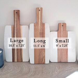 May include: Three wooden cutting boards with white marble inlays. The boards are labeled "Large 10.5" x 7.25", "Long 11.5" x 6", and "Small 9" x 7.25".
