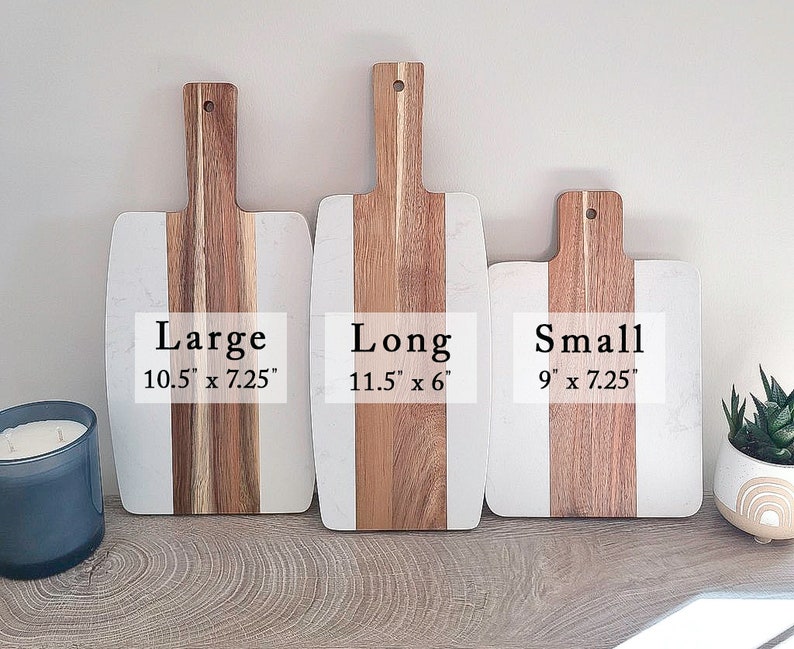 May include: Three wooden cutting boards with white marble inlays. The boards are labeled "Large 10.5" x 7.25", "Long 11.5" x 6", and "Small 9" x 7.25".