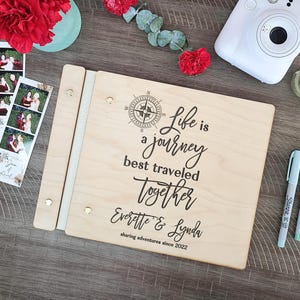 Puede incluir: Un &aacute;lbum de fotos de madera con un dise&ntilde;o de br&uacute;jula y el texto "Life is a journey best traveled together Everette & Lynda sharing adventures since 2022".