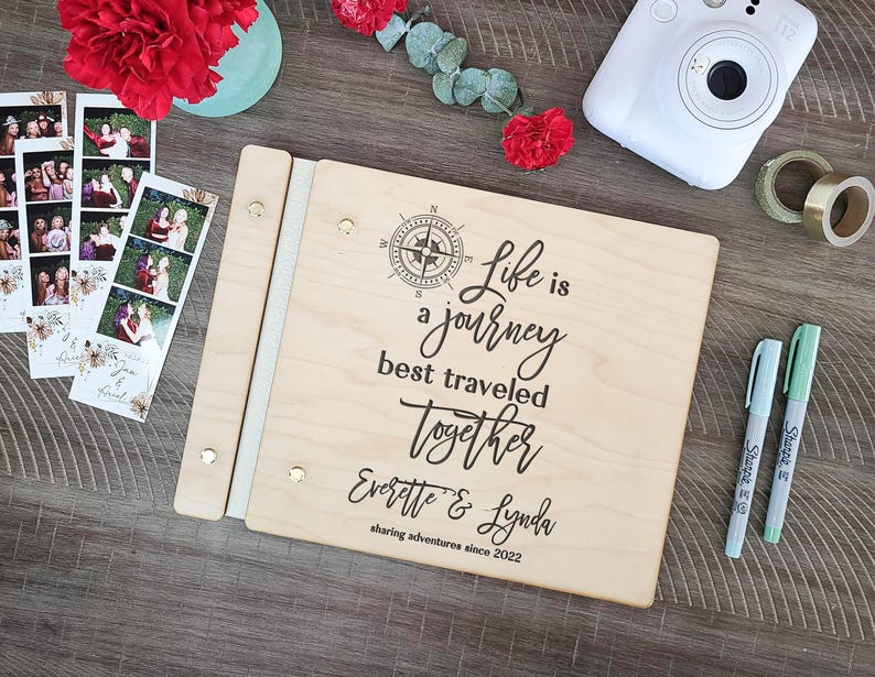 Puede incluir: Un &aacute;lbum de fotos de madera con un dise&ntilde;o de br&uacute;jula y el texto "Life is a journey best traveled together Everette & Lynda sharing adventures since 2022".
