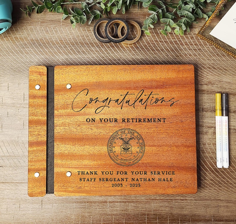 May include: A wooden guest book with a black spine and a laser engraved message that reads "Congratulations on your retirement." The book also features the Department of the Air Force seal and the text "Thank you for your service Staff Sergeant Nathan Hale 2005-2025."