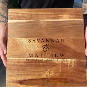 May include: A wooden chopping board with the names Savannah & Matthew engraved on it, along with the date August 14, 2023 and the location Newnan, GA.