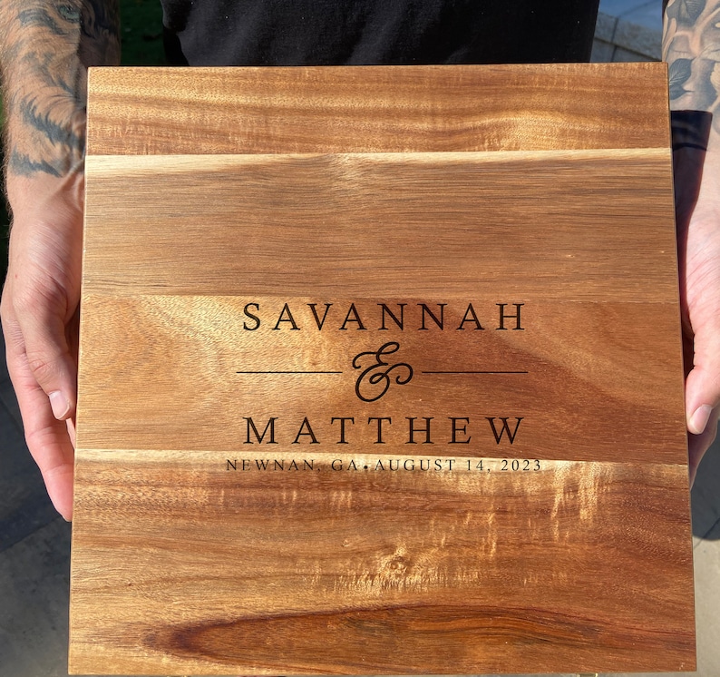 May include: A wooden chopping board with the names Savannah & Matthew engraved on it, along with the date August 14, 2023 and the location Newnan, GA.