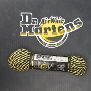 May include: A spool of black and yellow shoelace with a Dr. Martens label. The label says "Dr. Martens Air-Wair with Bouncing Soles".