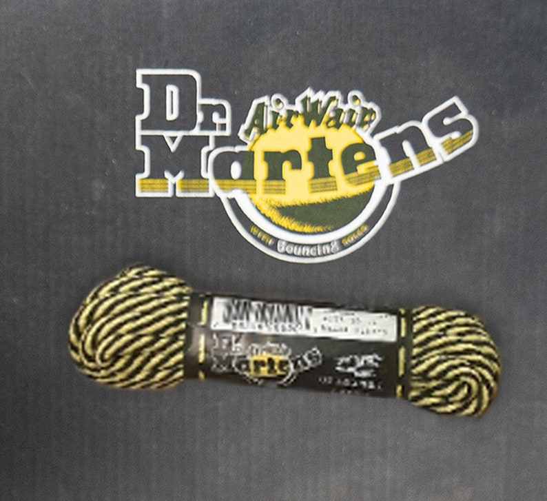 May include: A spool of black and yellow shoelace with a Dr. Martens label. The label says "Dr. Martens Air-Wair with Bouncing Soles".