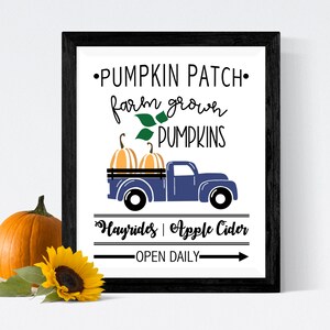 May include: A black framed sign with white text that reads "Pumpkin Patch, farm grown pumpkins, Hayrides, Apple Cider, Open Daily". A blue pickup truck with a bed full of pumpkins is illustrated on the sign.