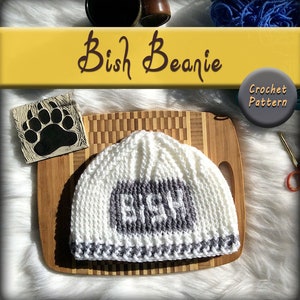 May include: White crochet beanie with a gray "Bish" word on the front. The beanie has a gray and white striped brim. Crochet pattern.