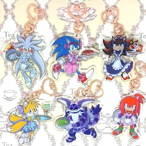 May include: Six colorful character keychains featuring Sonic the Hedgehog characters dressed in maid outfits. The characters include Sonic, Shadow, Tails, Silver, Knuckles, and Big the Cat. Each keychain has a gold-colored metal ring.