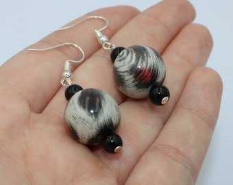 Pendientes hechos a mano con cuentas redondas de animal print gris y negro y detalles en rojo y cuentas de vidrio negro