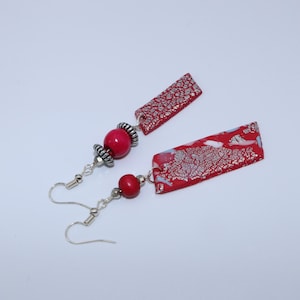 Handmade colorful earrings with pink pendants with colored and silver accents in the shape of a diamond