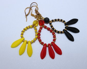 Pendientes hechos a mano con pequeñas cuentas y cuentas colgantes en forma de espada en rojo, negro y amarillo.